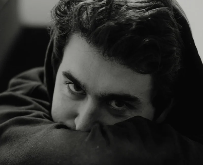 Młody mężczyzna z zamyślonym wyrazem twarzy – symbol stresu i psychicznych przyczyn zaburzeń erekcji w młodym wieku