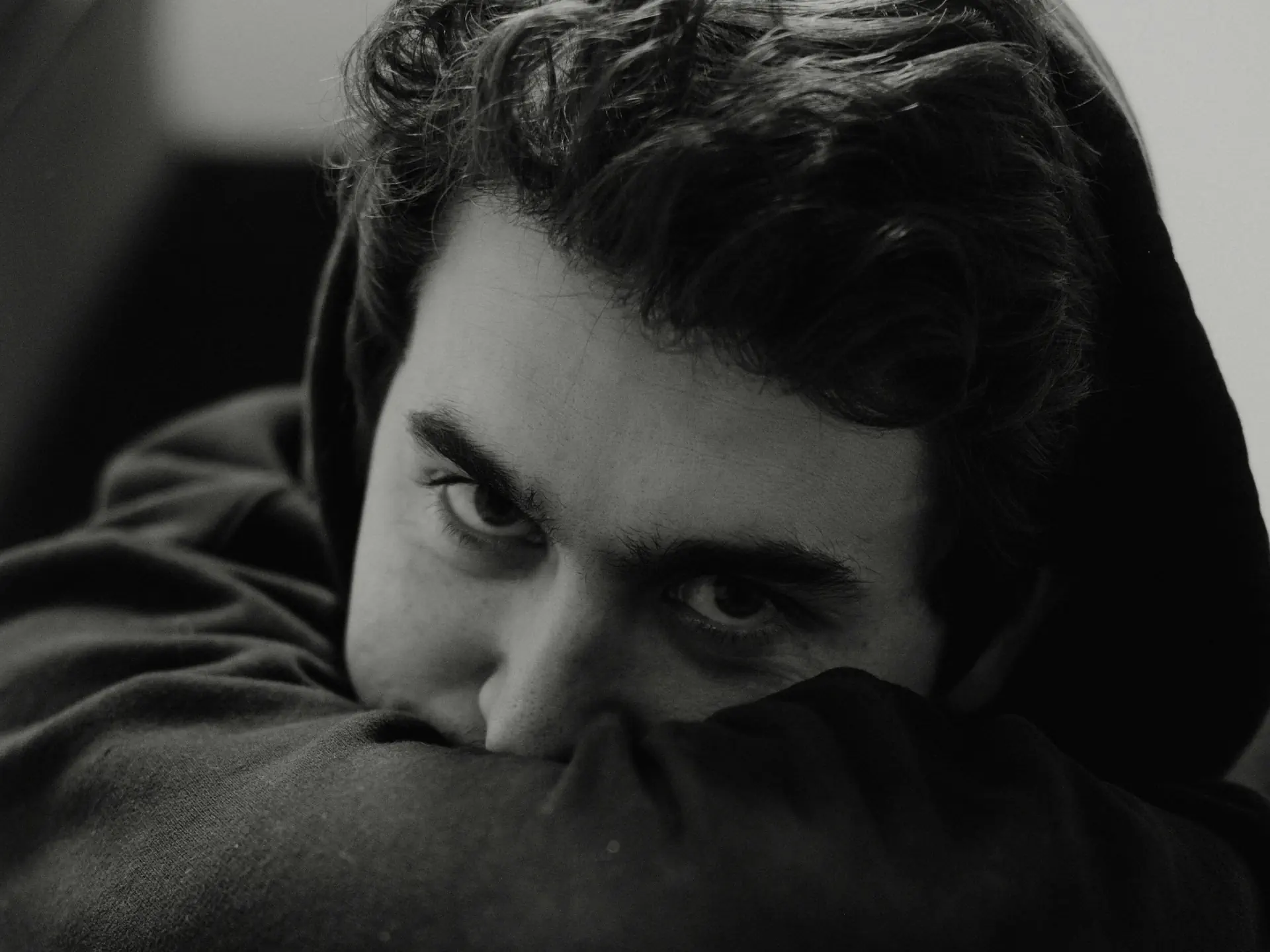 Młody mężczyzna z zamyślonym wyrazem twarzy – symbol stresu i psychicznych przyczyn zaburzeń erekcji w młodym wieku