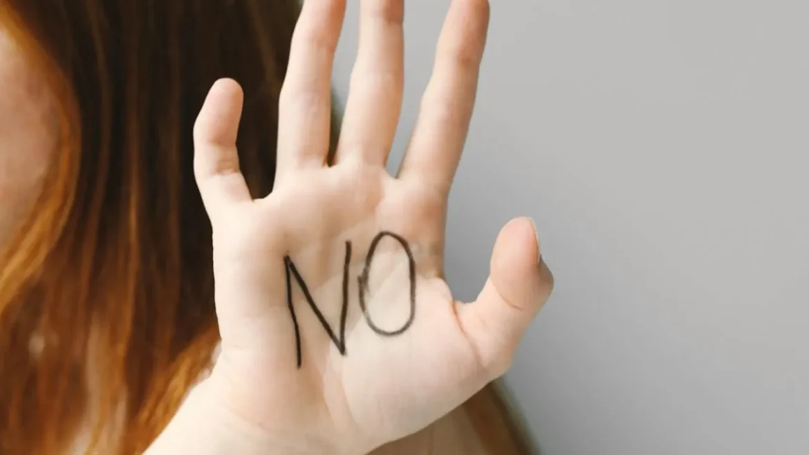 Uniesiona dłoń z napisem „NO” na wewnętrznej stronie, symbolizująca stawianie granic, asertywność i odmowę.