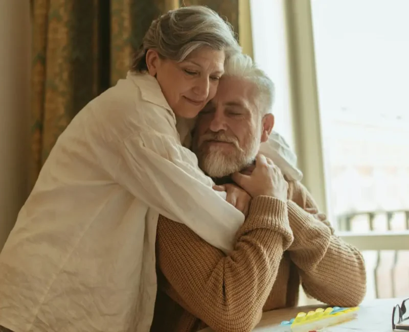 Dojrzała para przytula się czule w domowym wnętrzu, wyrażając bliskość, czułość i intymność w późniejszym wieku.