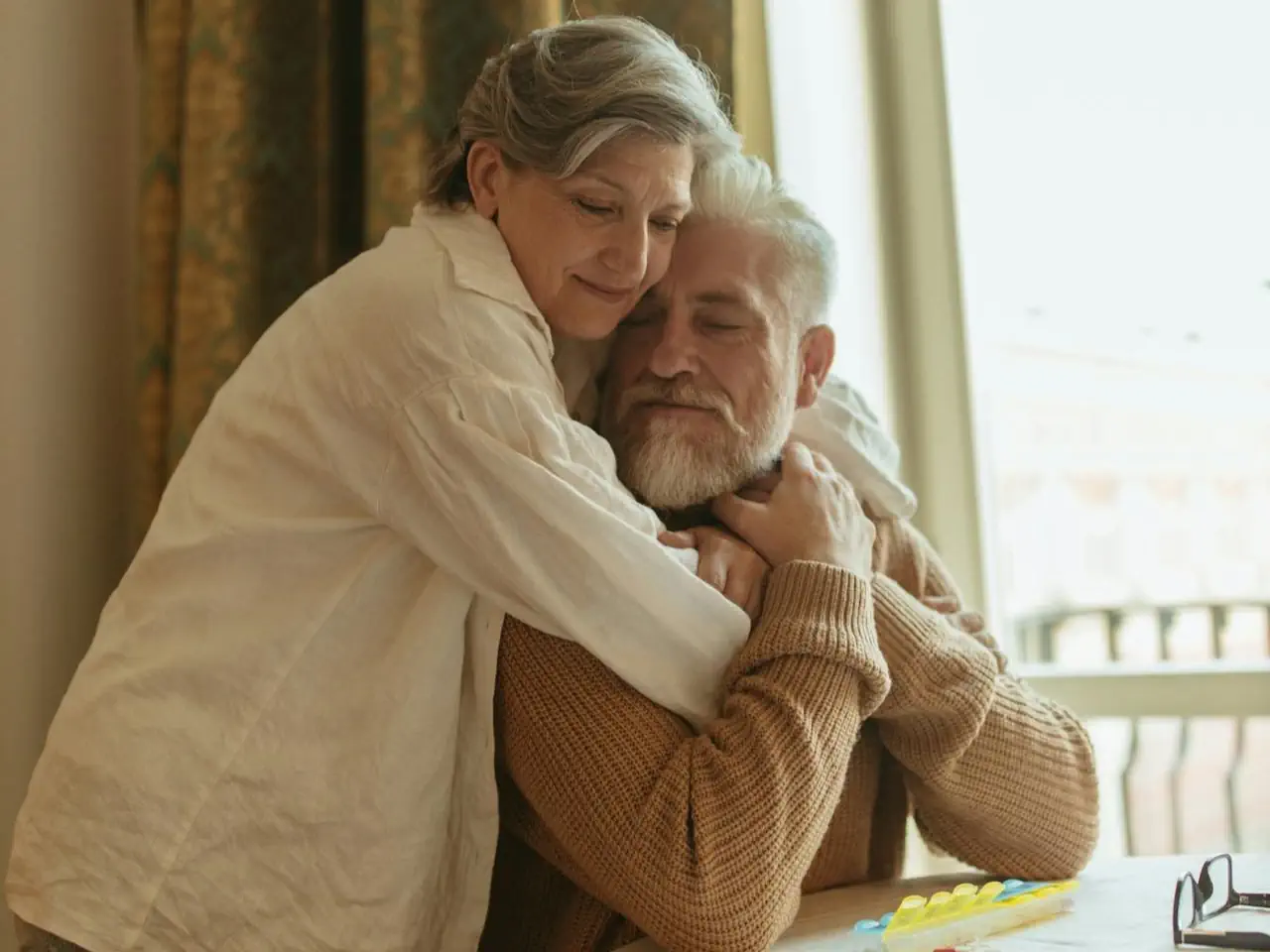 Dojrzała para przytula się czule w domowym wnętrzu, wyrażając bliskość, czułość i intymność w późniejszym wieku.